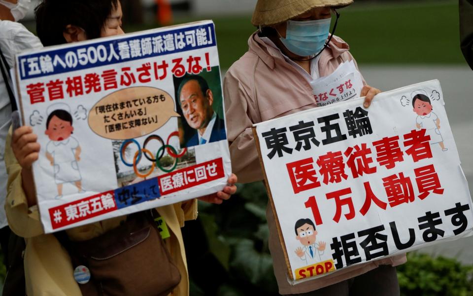 Anti-Olympics group members hold banners denouncing government's requests on dispatching doctors and nurses to help out with the Games - Reuters