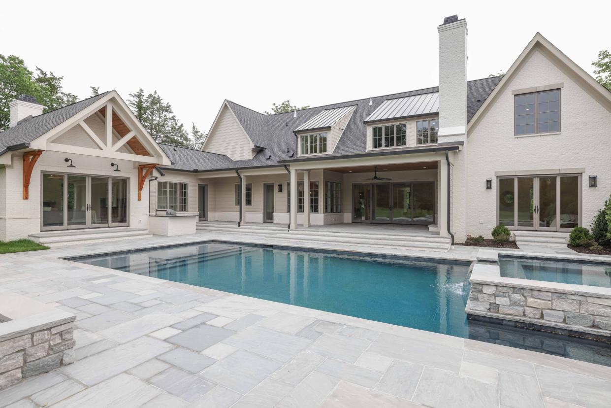 The pool deck at 649 Brook Hollow Road features a stone hot tub with a waterfall, a covered patio with a gas fireplace, and a built-in kitchen with a grill.