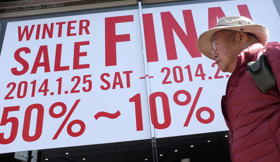 In this Monday, Feb. 17, 2014 photo, a man walks by a clothing store with a winter sale advertisement in Tokyo. Japan's consumer price index rose 1.3 percent in January and factory production also climbed, suggesting the recovery in the world's third-largest economy is holding steady ahead of an April 1 tax hike. A raft of data released Friday suggest the economy may need still more help in weathering the 3 percent tax increase in April as many economists forecast a contraction will follow as consumers and businesses adjust to higher costs. (AP Photo/Shizuo Kambayashi)