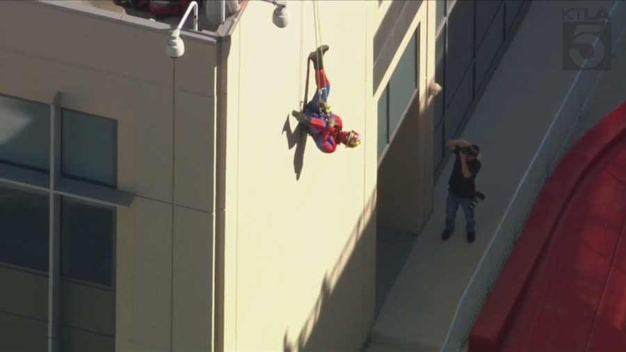 A Search and Rescue team member dressed as Spider-Man hangs upside down from the roof of Ventura County Medical Center on Oct. 31, 2023.