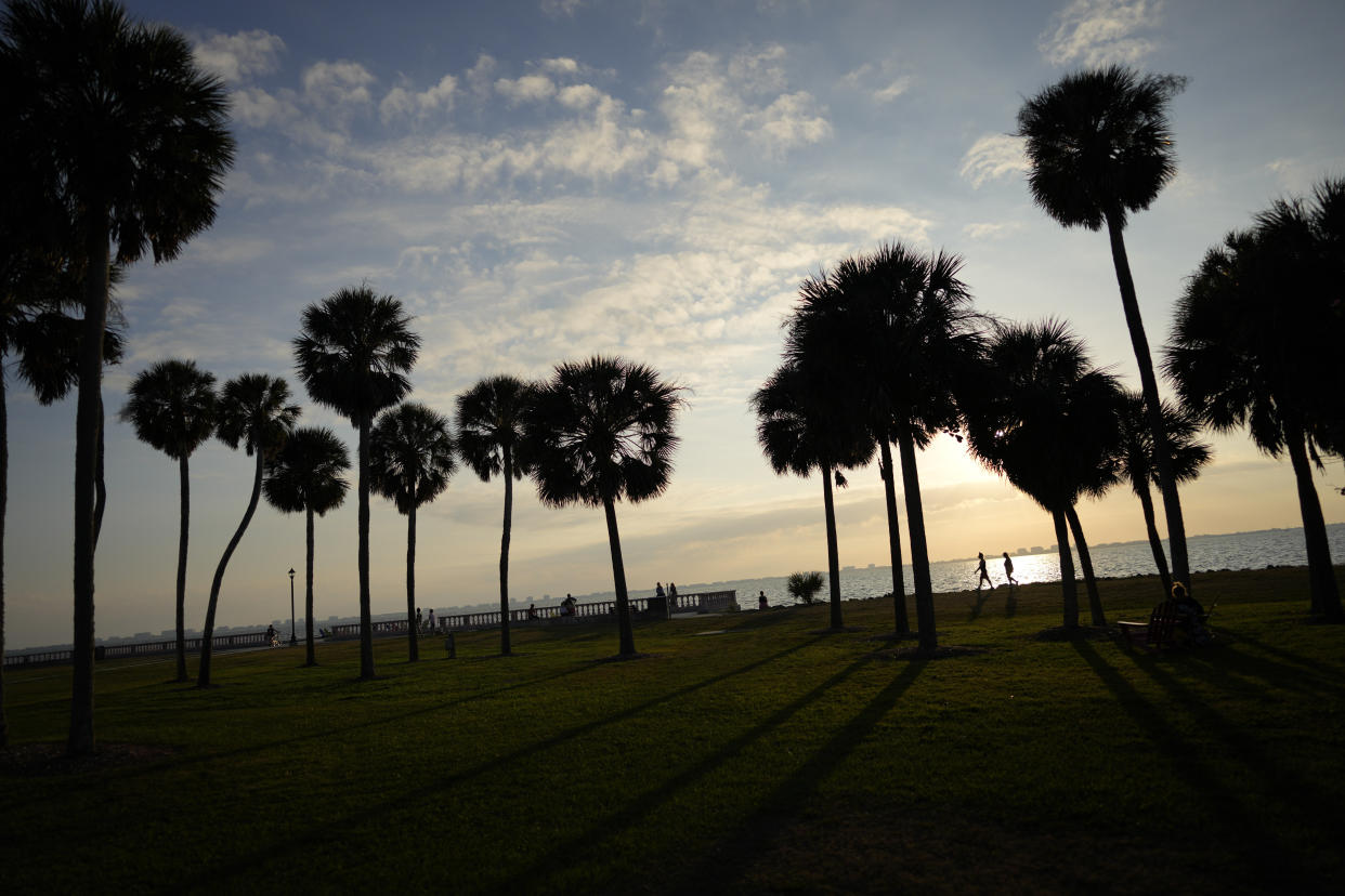 People walk along the waterfront at New College of Florida, Tuesday, Feb. 28, 2023, in Sarasota, Fla. Students and faculty compare the upheaval at Florida's public honors college to a "hostile takeover" that feels even more jarring because of what the school has represented to so many students for so many years: a haven of open-mindedness and acceptance in a place of idyllic beauty, with palm-tree-lined paths along a stretch of white-sand coast. (AP Photo/Rebecca Blackwell)