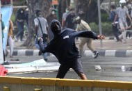 A student protester throws a rock at police during a clash in Jakarta, Indonesia, Thursday, Oct. 8, 2020. Thousands of enraged students and workers staged rallies across Indonesia on Thursday in opposition to the new law they say will cripple labor rights and harm the environment. (AP Photo/Tatan Syuflana)