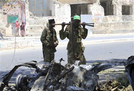 Somali government soldiers look at the wreckage of a mangled car used by a suicide bomber at the scene of a bomb attack next to a tea shop in the suburbs of capital Mogadishu February 27, 2014. The Islamist militant suicide bomber drove the car into the Mogadishu cafe frequented by members of the security forces on Thursday, killing at least 10 people and blowing the place to bits. Al Shabaab said it had carried out the attack, which followed an assault by its fighters on the president's palace in the Somali capital last week. REUTERS/Omar Faruk