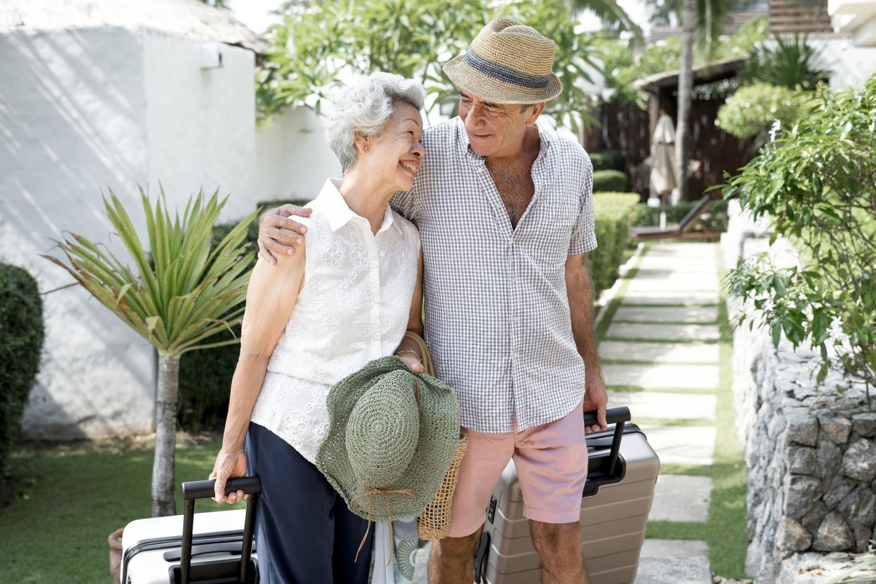 senior couple with luggage walking together at resort