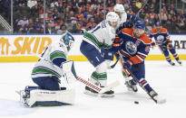 Vancouver Canucks' goalie Casey DeSmith (29) makes the save as Akito Hirose (41) and Edmonton Oilers' Connor McDavid (97) battle for the puck during the second period of an NHL hockey game in Edmonton, Alberta, Saturday, Oct. 14, 2023. (Jason Franson/The Canadian Press via AP)