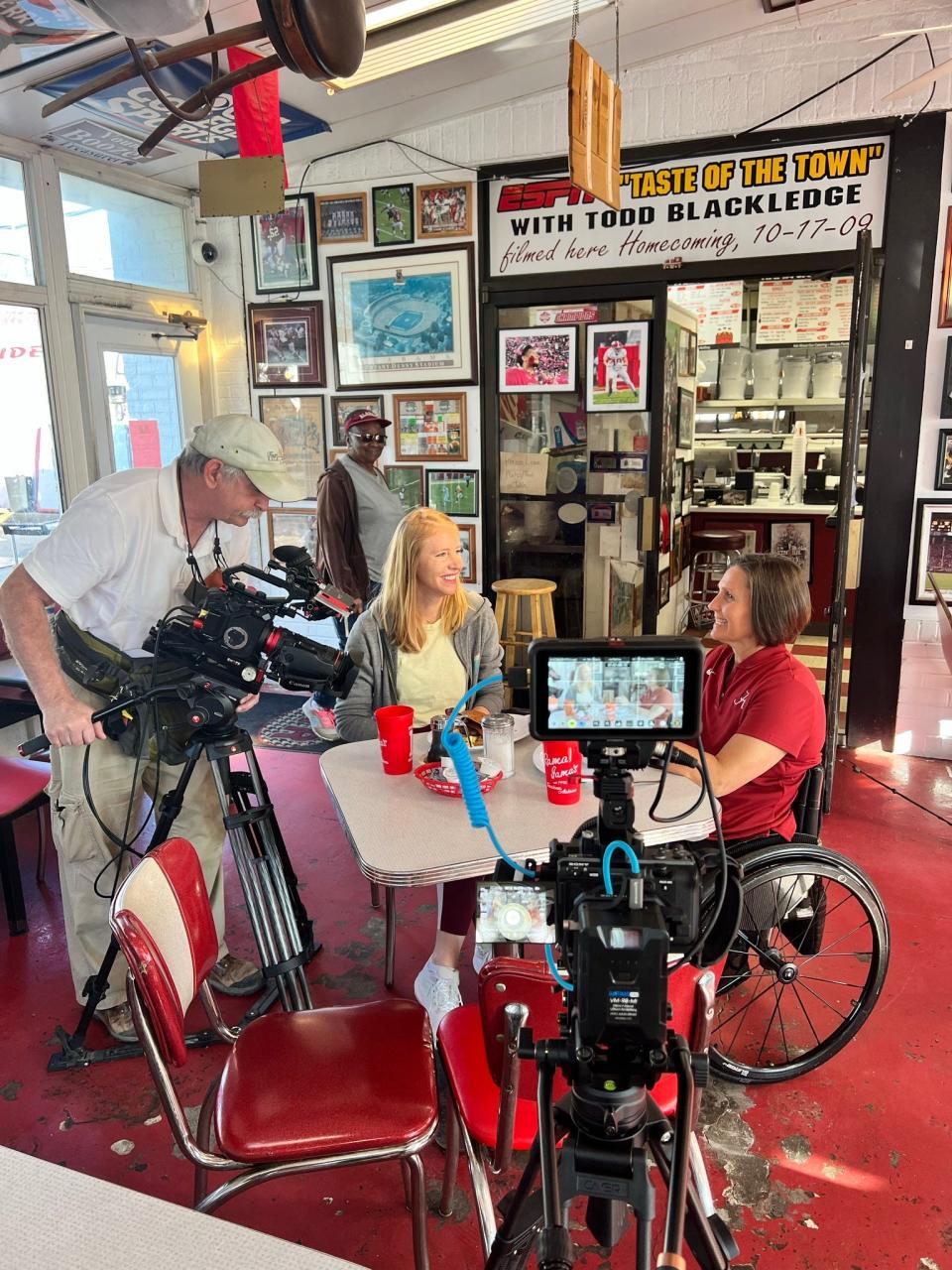 In this behind-the-scenes photo, "Travels with Darley" host Darley Newman interviews Margaret Stran, of the University of Alabama adapted athletics program, at Rama Jama's.