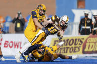 Wyoming quarterback Levi Williams (15) is hit by Kent State linebacker A.J. Musolino (19) and safety Dean Clark (3) after scrambling with the ball during the first half of the Idaho Potato Bowl NCAA college football game, Tuesday, Dec. 21, 2021, in Boise, Idaho. (AP Photo/Steve Conner)