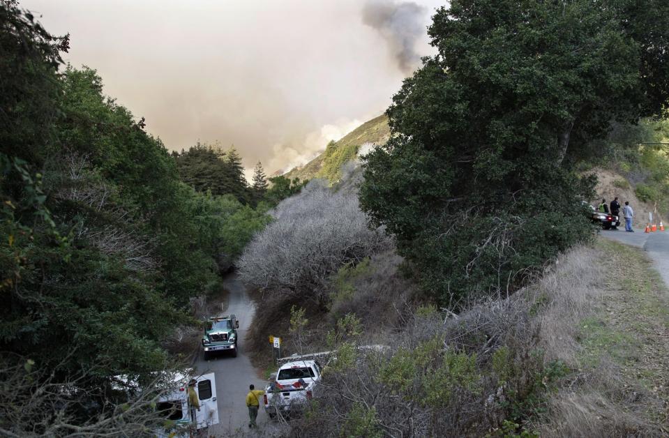 Police and fire vehicles sit at the entrance to a canyon during a wild fire in Big Sur