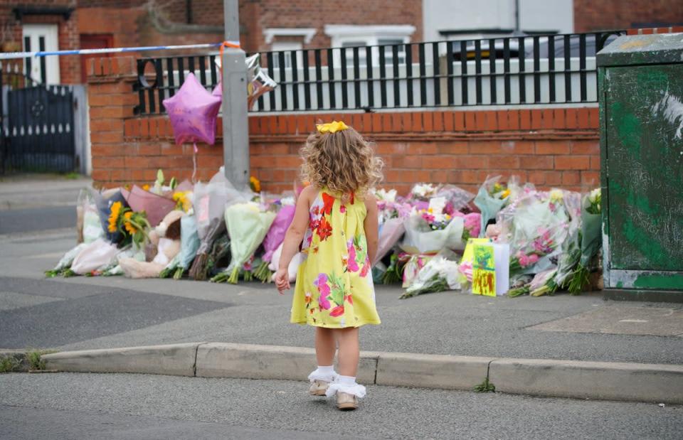 24 August 2022: A young girl lays a tribute in Kingsheath Avenue, Knotty Ash, Liverpool, where nine-year-old Olivia Pratt-Korbel was fatally shot on Monday night (PA)