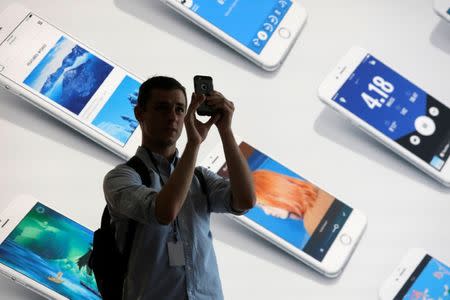 FILE PHOTO: A man uses his iPhone during a preview event at the new Apple Store Williamsburg in Brooklyn, New York, U.S., July 28, 2016. REUTERS/Andrew Kelly/File Photo