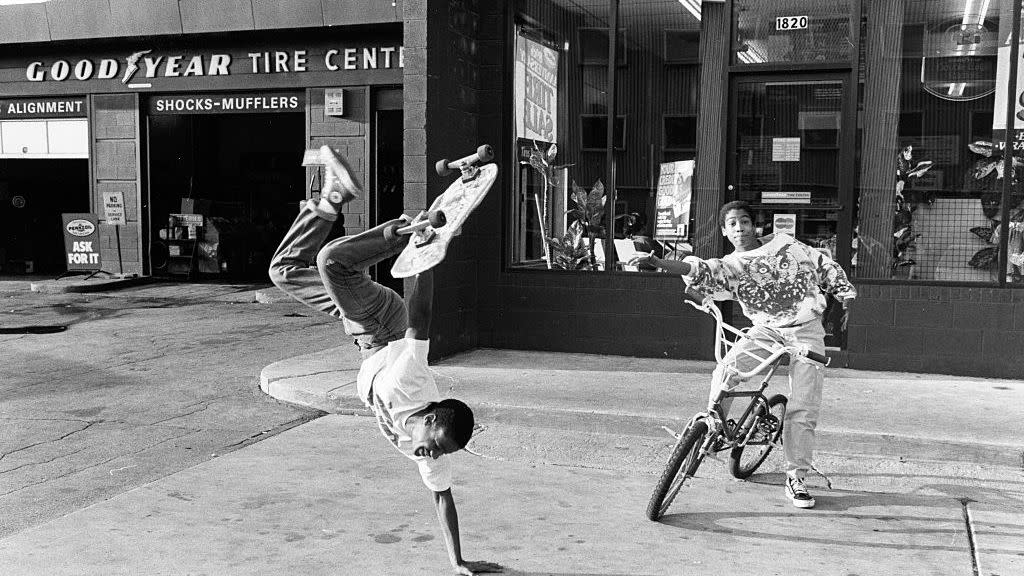 young man doing a one arm handstand with a skateboard