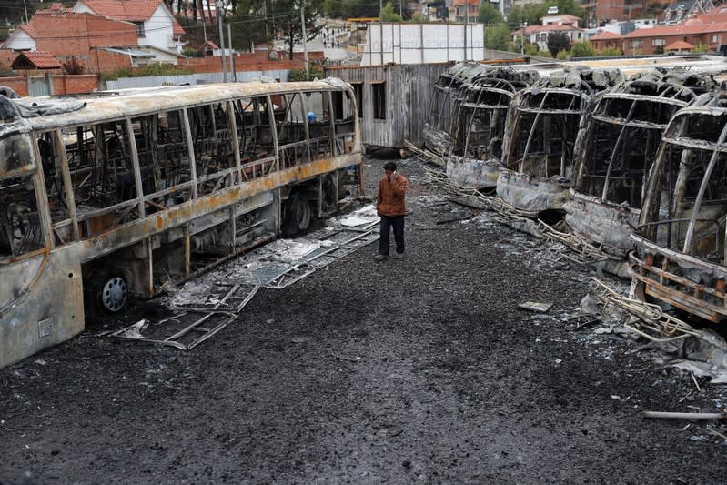 A man walks past buses burned during a protest after Bolivia's President Evo Morales announced on Sunday that he was resigning, in La Paz