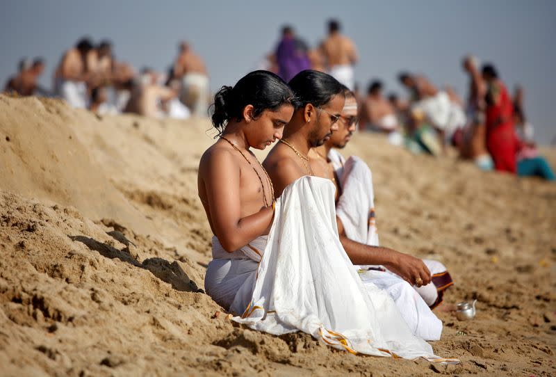 People perform special prayers during the annular solar eclipse and for the victims of the 2004 tsunami on the 15th anniversary of the disaster, at Marina beach in Chennai