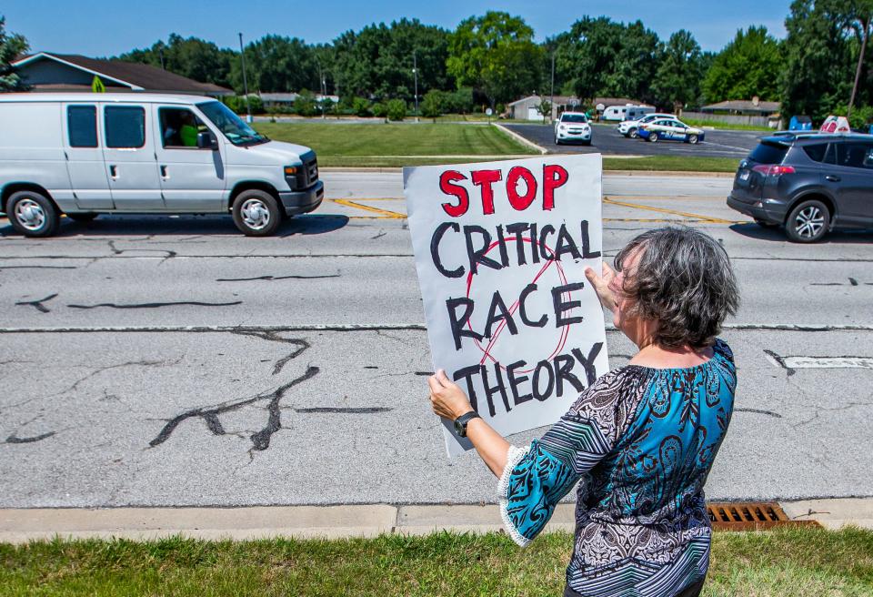 Kelly Havens holds a sign for passing cars to see Friday during a protest outside Penn-Harris-Madison offices. She is among a group of people raising questions about CRT and social emotional learning in the school district.