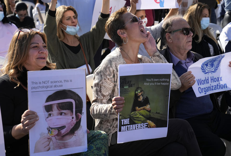 Protesters hold placards and shout slogans during a rally to protest measures imposed against people who are not vaccinated, in Beirut, Lebanon, Saturday, Jan. 8, 2022. Vaccination is not compulsory in Lebanon but in recent days authorities have become more strict in dealing with people who are not inoculated or don’t carry a negative PCR test. (AP Photo/Hussein Malla)