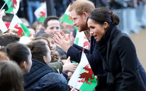 Prince Harry and his fiancee Meghan Markle shake hands with children as they arrive to a walkabout - Credit: Chris Jackson /Getty