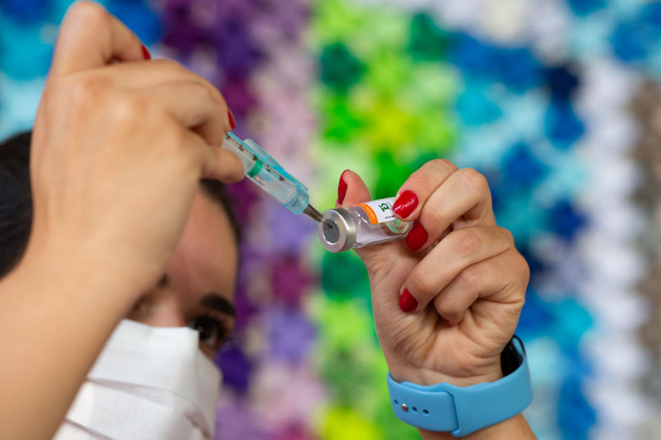 BRASILIA, BRAZIL - MARCH 29: Health professional prepares a vaccine against coronavirus (COVID-19) in front of the panel in honor of the fatal victims of the disease amidst the coronavirus pandemic in Centro de Saúde 07 on March 29, 2021 in Brasilia Ceilandia, Brazil. Volunteers made 5,800 lotus flower origami, a symbol of hope, to honor each of Covid's victims in the capital of Brazil. Brazil has over 12,573,000 confirmed positive cases of Coronavirus and has over 313,866 deaths. (Photo by Andressa Anholete / Getty Images)