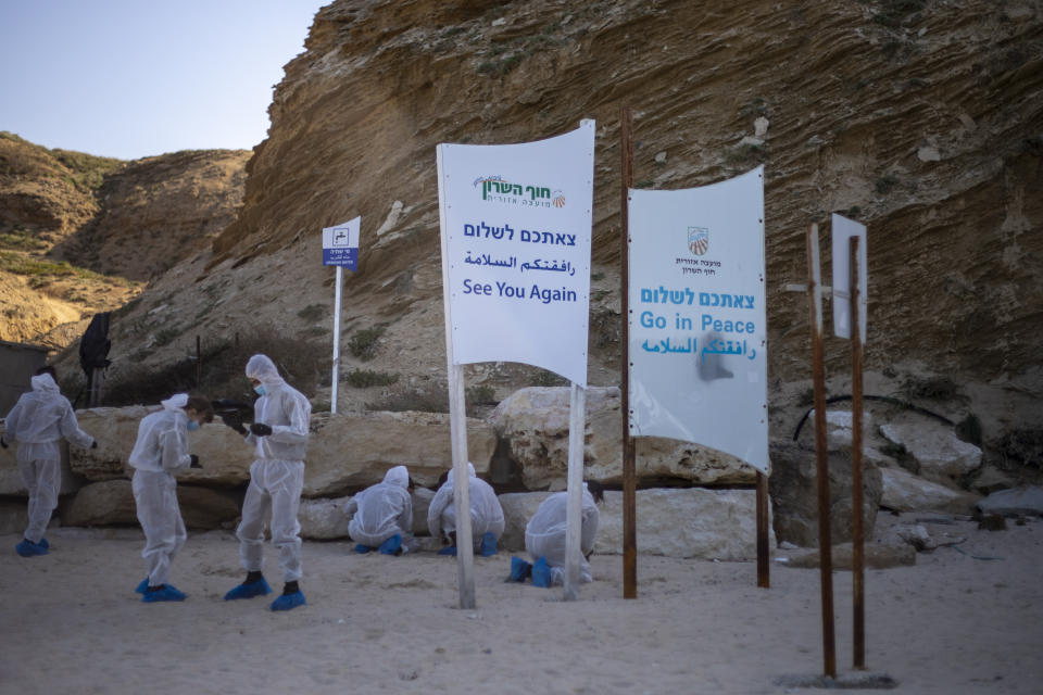 Israeli soldiers wearing protective suits clean tar from a beach after an oil spill in the Mediterranean Sea in Sharon Beach Nature Reserve, near Gaash, Israel, Monday, Feb. 22, 2021. (AP Photo/Ariel Schalit)