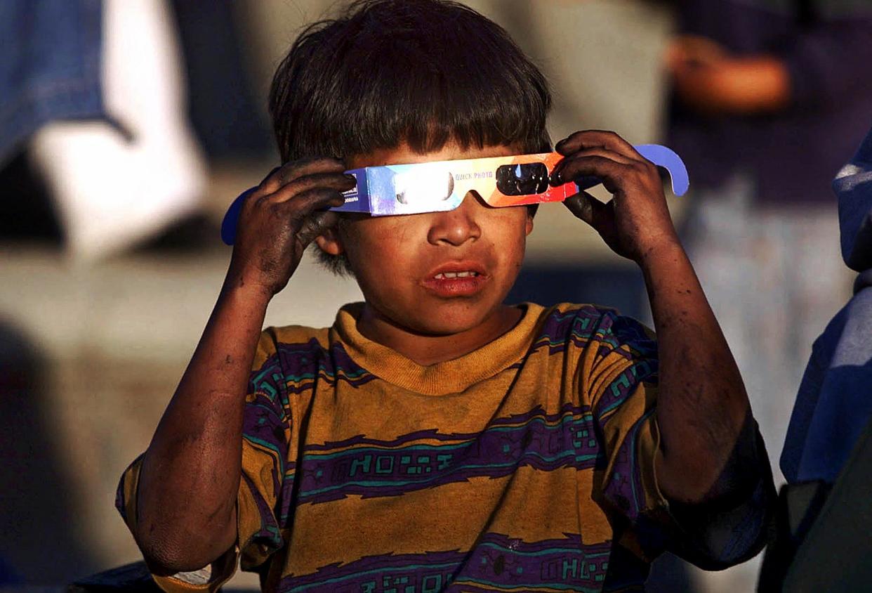 2001: A young boy observers a partial eclipse with protective lenses in Guatemala City. 