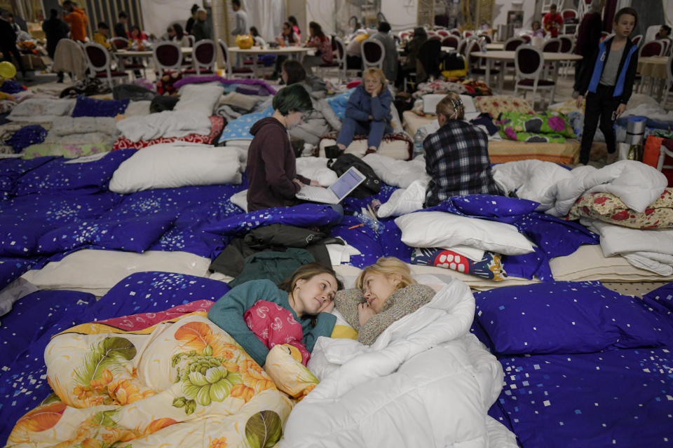 FILE - Anna Karpenko, left, 32, who fled the Russian invasion from Chornomorsk with her son, speaks to her mother inside a ballroom converted into a makeshift refugee shelter at a 4-star hotel & spa, in Suceava, Romania, Friday, March 4, 2022. Around 2.5 million people have fled Ukraine in the two weeks since Russia invaded. Most have fled to the European Union. (AP Photo/Andreea Alexandru, File)