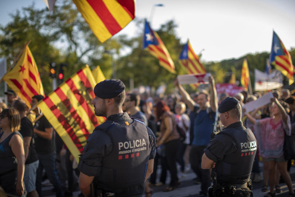Catalan police officers stand guard as pro-independence demonstrators march during a protest in Sabadell, near Barcelona, Spain, Saturday, Sept. 28, 2019. Several thousand people have marched in a town near Barcelona to protest the jailing of seven Catalan separatists for allegedly planning to commit violent acts of terrorism with explosives. (AP Photo/Emilio Morenatti)
