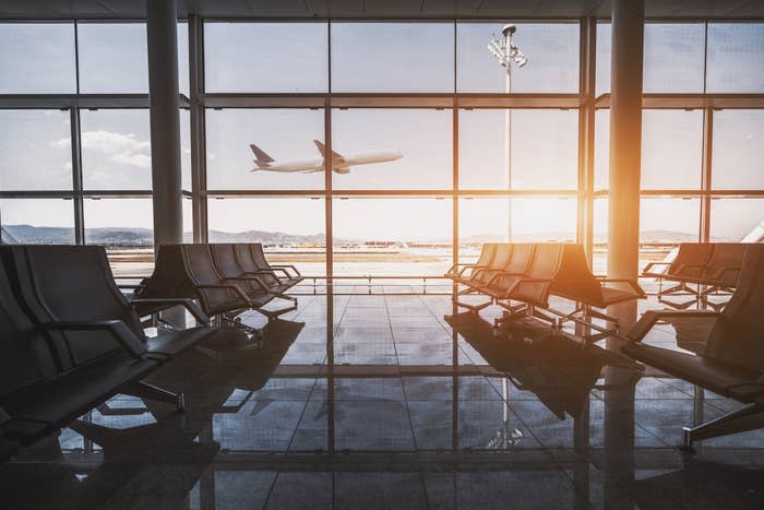 Inside of an airport as a plane is taking off outside