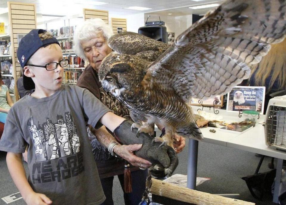 Doris Mager watches her beloved great horned owl E.T. land on the covered arm of Ian Pettyjohn, then 9, in this 2016 file photo in West Richland, Wash., when she was 90.