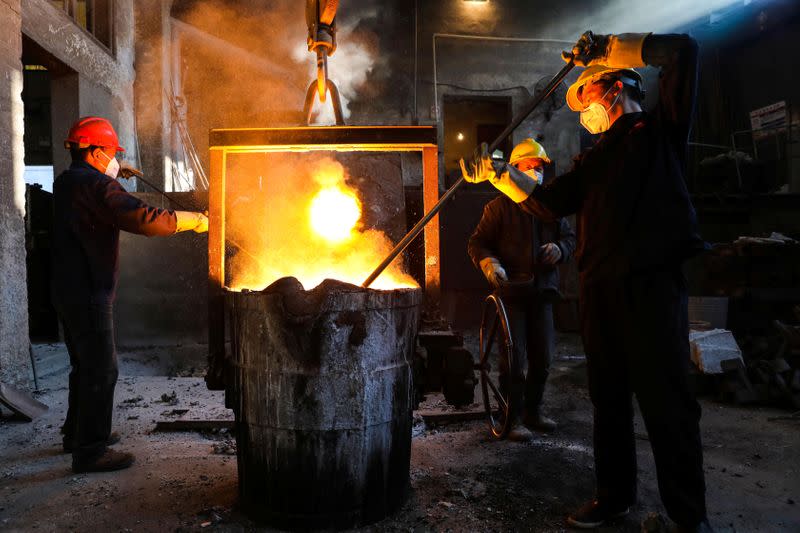 Workers wearing face masks work next to a furnace at a steel plant in Hangzhou, Zhejiang