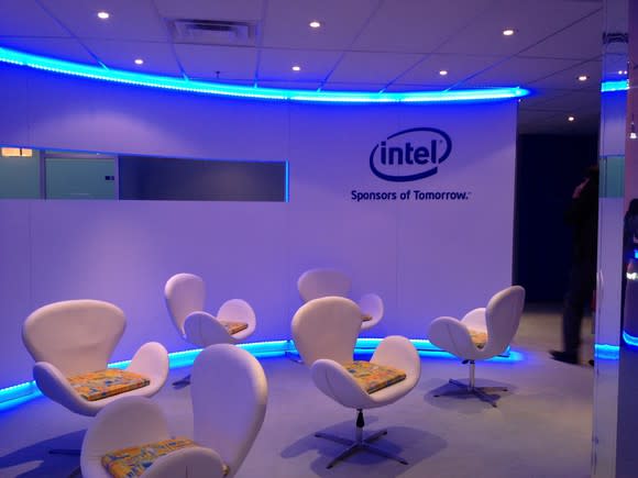 Room with six chairs and a curved wall, flanked by neon blue trim, with the Intel logo on the wall.