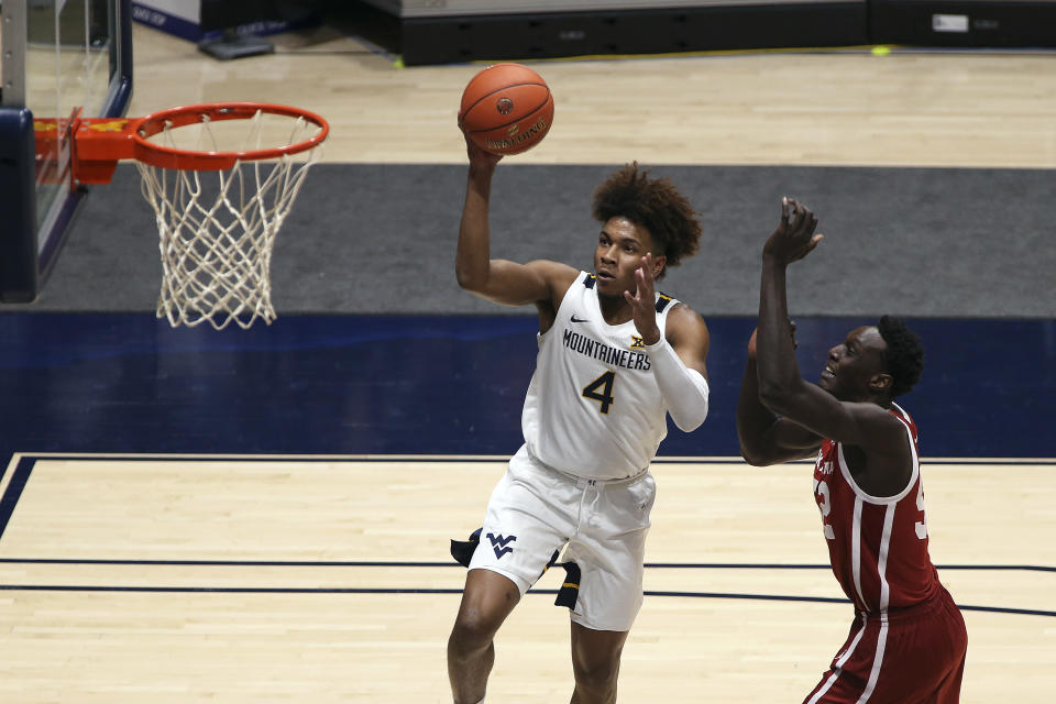 West Virginia guard Miles McBride (4) drives to the basket past Oklahoma forward Kur Kuath (52) during the first half of an NCAA college basketball game Saturday, Feb. 13, 2021, in Morgantown, W.Va. (AP Photo/Kathleen Batten)