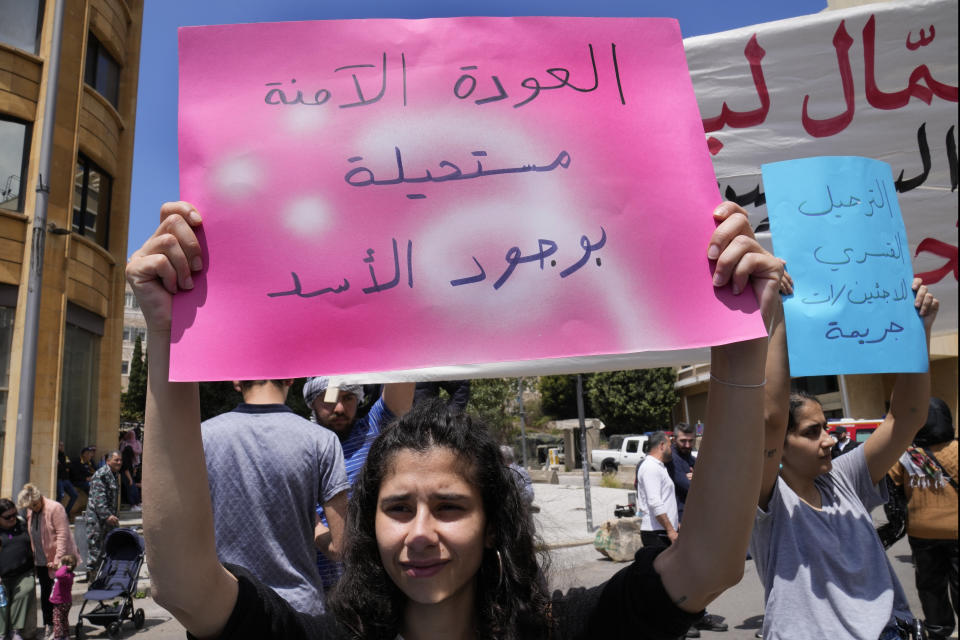 A protester holds a sign reading "A safe return is impossible while Assad is present" in Arabic at a workers' day march held by leftist groups in Beirut, Lebanon, Monday, May 1, 2023. The slogans came in response to increased pressure by Lebanese authorities on Syrian refugees in recent weeks, including raids, arrests and deportations. (AP Photo/Hussein Malla)
