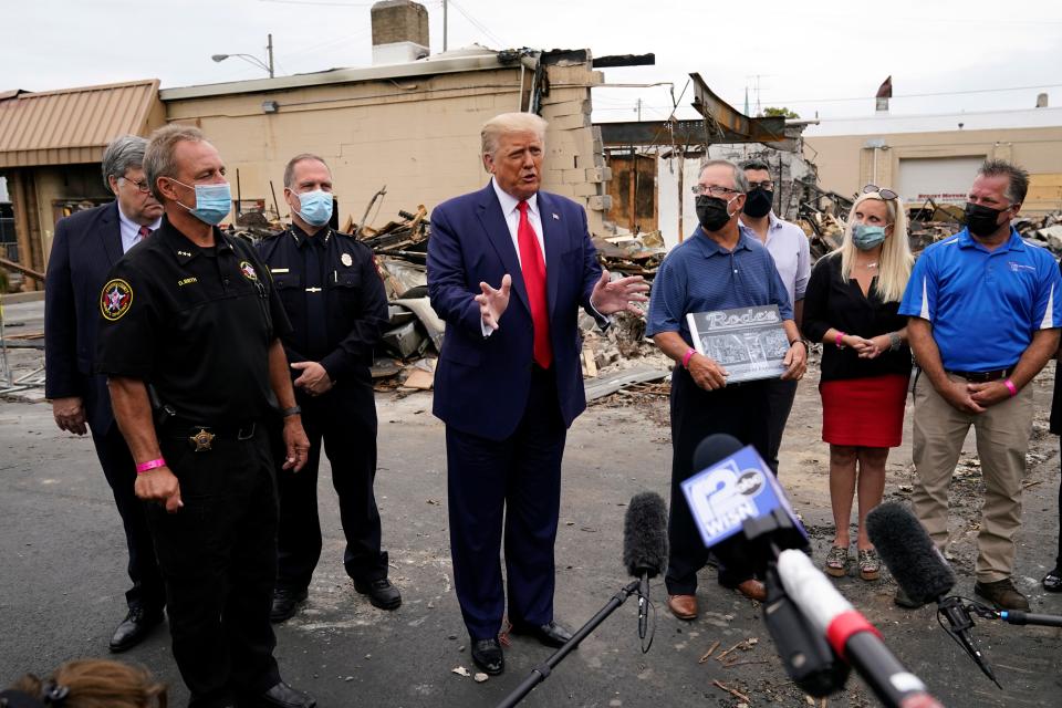 President Donald Trump talks with reporters as he tours an area damaged during demonstrations in Kenosha, Wis.