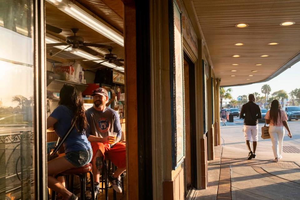 Customers sit at the bar at Peaches Corner and watch visitors pass on Ocean Boulevard in Myrtle Beach on Friday. Grand strand residents and visitors head for the beach on the first sunny weekend of Spring. March 24, 2023.