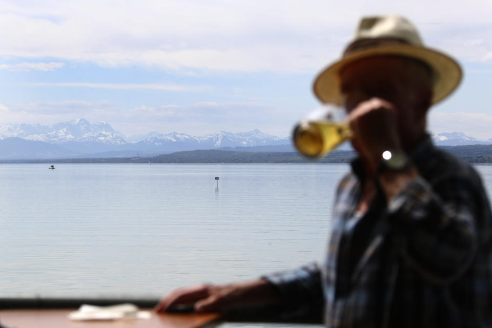 An elderly man drinks beer during sunny weather on the re-opening day of beer gardens, following the lifting of measures to avoid the spread of the corona virus, at lake 'Ammersee' in front of the alps in Inning, Germany, Monday, May 10, 2021. (AP Photo/Matthias Schrader)