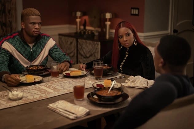 Three people, including Daniel Bellomy as Zeke, sitting at a dinner table looking confused