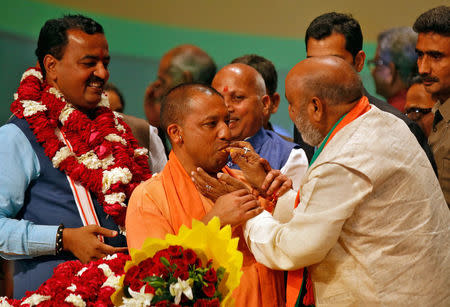 India’s ruling Bharatiya Janata Party (BJP) leader Yogi Adityanath (C) is offered sweets after he was elected as Chief Minister of India’s most populous state of Uttar Pradesh, during the party lawmakers' meeting in Lucknow, India March 18, 2017. REUTERS/Pawan Kumar