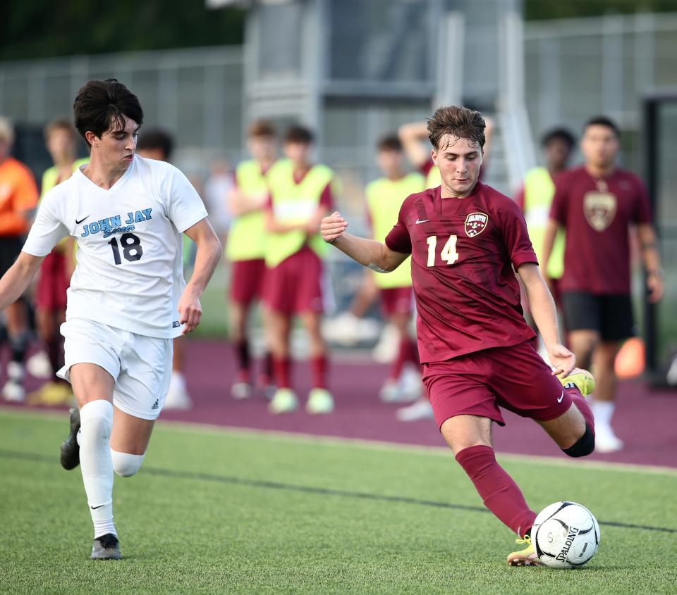 Arlington’s Evan Simmons crosses the ball ahead of John Jay’s Matthew Zella during Wednesday’s game in Freedom Plains.