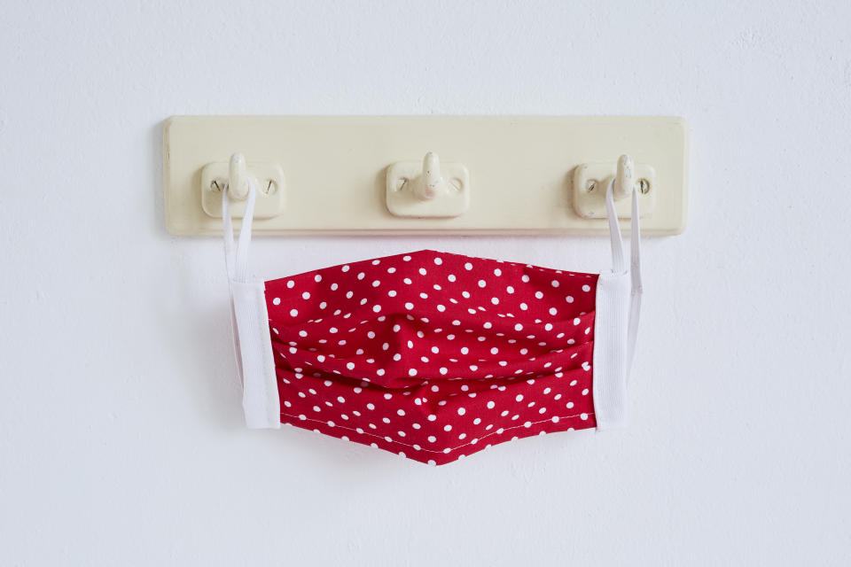 Still life of a red self made face mask hanging at a coat hook, DIY sewing project