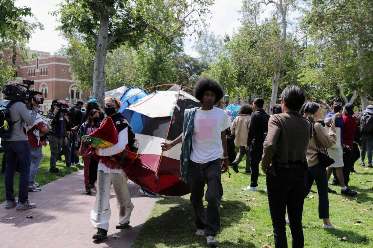 PHOTO: People carry a tent as USC Safety officers try to disperse students who protest in support of Palestinians, at the University of Southern California's Alumni Park, in Los Angeles, on April 24, 2024. (Zaydee Sanchez/Reuters)