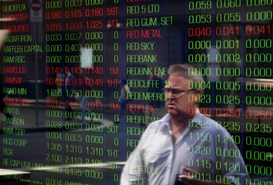 A potential investor, looking confused, is reflected in the window of the Sydney Stock Exchange.