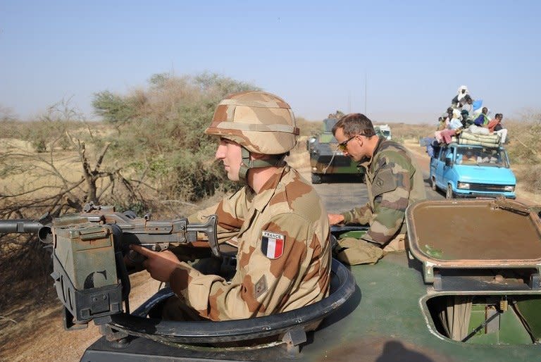 A local truck drives by a convoy of French army vehicles heading toward Gao, on February 7, 2013. A suicide bomber blew himself up in northern Mali as a dramatic turn towards guerrilla tactics by Islamists and an outbreak of fighting among soldiers in the capital show the war is far from won for the embattled nation