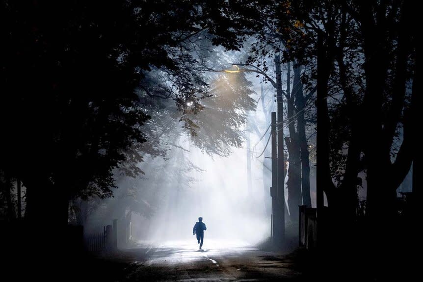 A silhouetted man walks through a beam of light in a forest SurrealEstate 201 