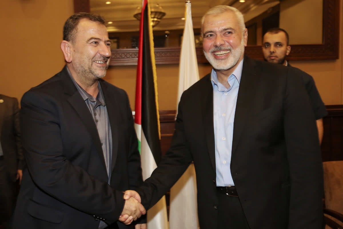 Ismail Haniyeh, right, the head of the Hamas political bureau, shakes hands with Saleh Arouri (AP)