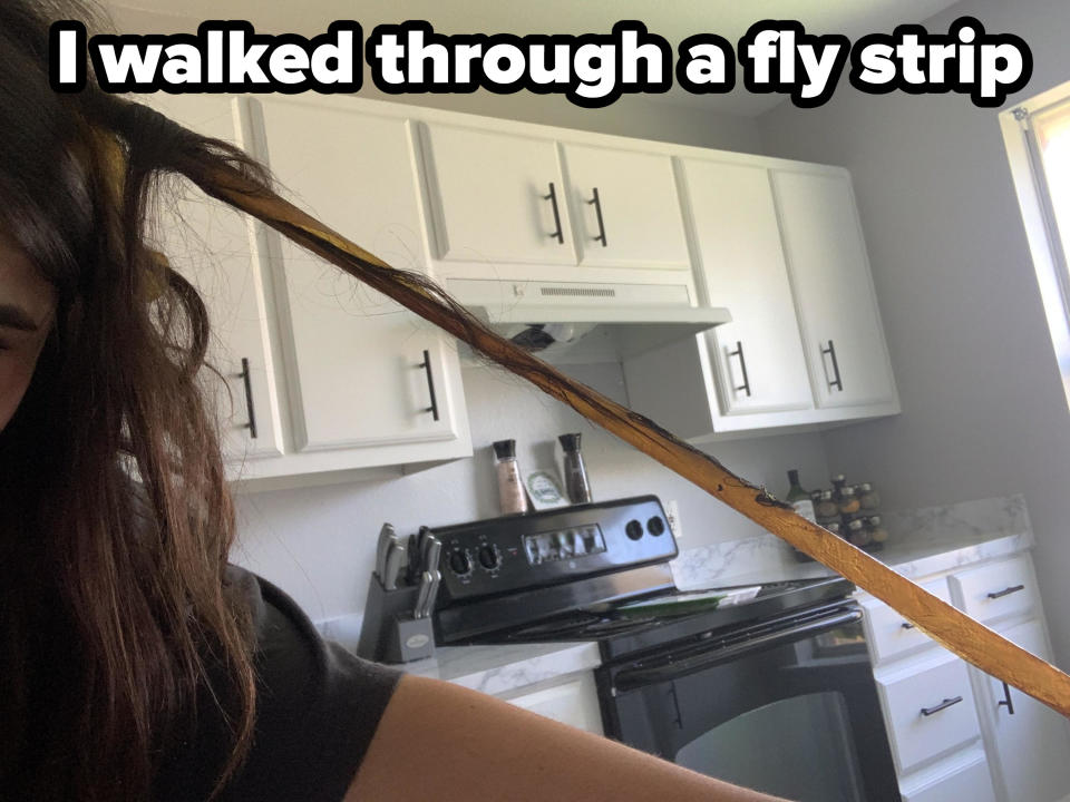 A fly strip stuck in a person's hair in a kitchen