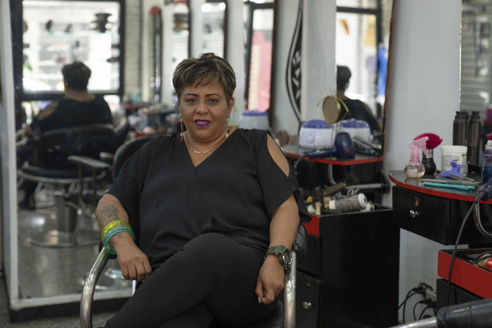 Luzmilla Arrechedera, a hair stylist, poses for a picture at the salon where she works in Caracas, Venezuela, Thursday, Feb. 23, 2023. Arrechedera's only child was killed in a robbery seven years pior and two of her three grandchildren moved to Spain with their mother. (AP Photo/Ariana Cubillos)