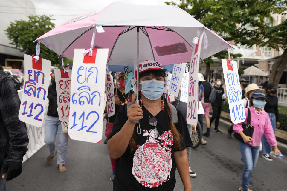 A pro-democracy supporter wears a face mask with the umbrella with sign saying "No to Article 112", a legal provision in Thailand's Criminal Code concerning any defamation of the monarchy, as she participates in a rally in Bangkok, Thailand, Thursday, June 24, 2021. Anti-government protests expected to resume in Bangkok after a long break due partly to a surge in COVID-19 cases. Gatherings are planned for several locations across the capital, despite health officials mulling a week-long lockdown in Bangkok to control a rampant virus surge. (AP Photo/Sakchai Lalit)