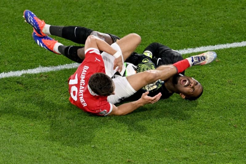 Austria's Christoph Baumgartner (L) collides with France goalkeeper Mike Maignan during the UEFA Euro 2024 Group D soccer match between Austria and France at the Duesseldorf Arena. Fabian Strauch/dpa