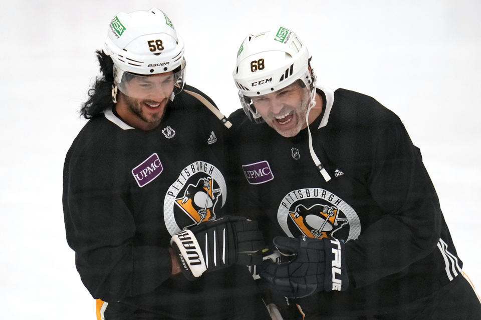 Pittsburgh Penguins' Kris Letang, left, wearing a mullet wig, shares a laugh with former Penguins player Jaromir Jagr during NHL hockey practice, Saturday, Feb. 17, 2024, in Cranberry, Pa. Jagr, who spent 11 seasons playing for the Penguins, will have his No. 68 officially retired during a pre-game ceremony before an NHL hockey game between the Los Angeles Kings and Penguins on Sunday. (AP Photo/Gene J. Puskar)