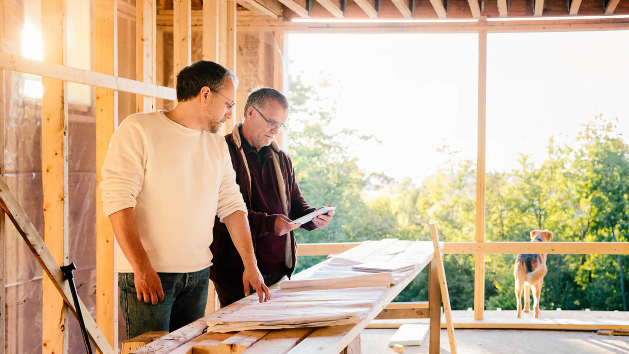 Architect comparing physical plans to tablet version with a the contractor.