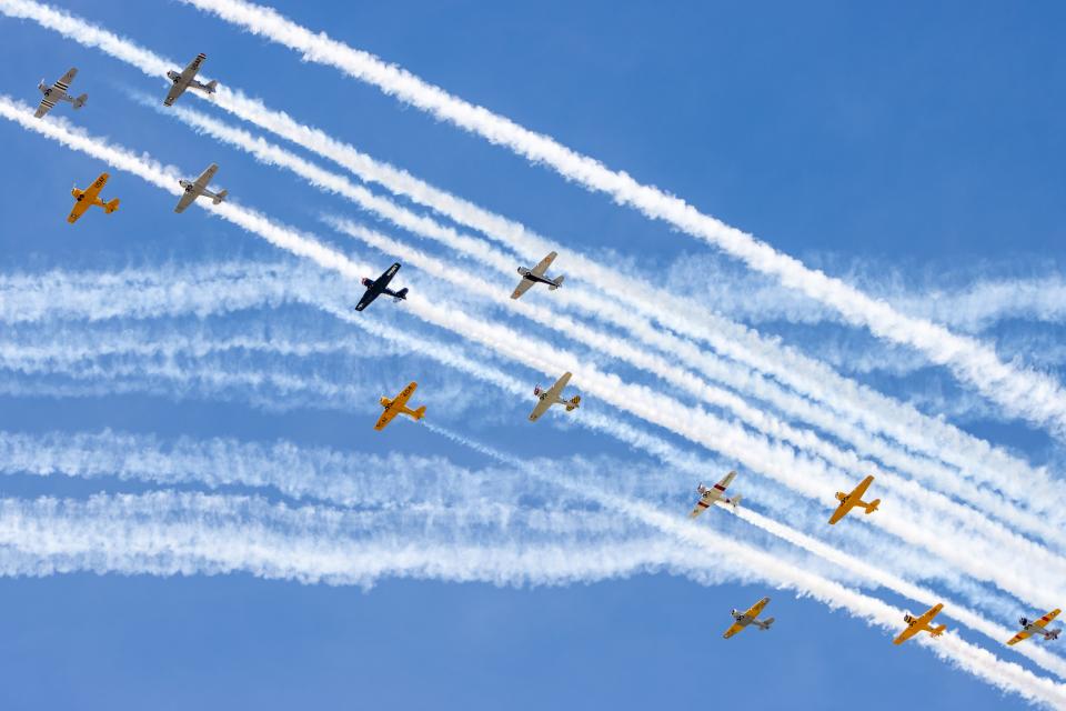 Warbird aircraft leave smoke trails across the sky during the afternoon air show at EAA AirVenture Oshkosh 2022.